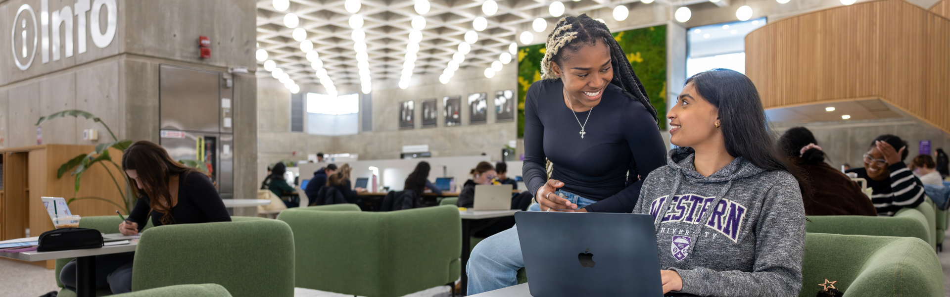 Two students looking at a laptop together, sitting on a couch in Weldon Library.