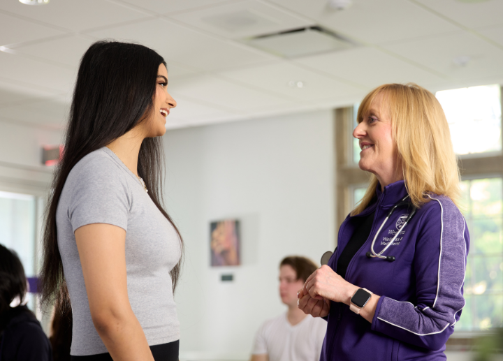 a nurse smiling as she greets a student.