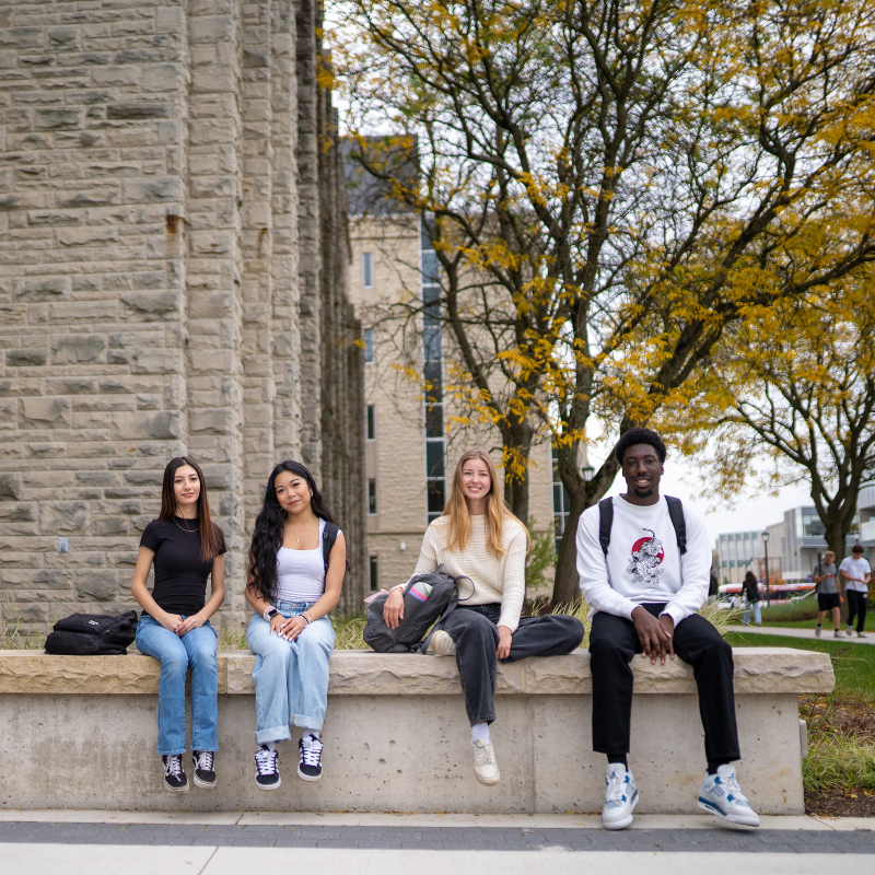 a group of students walking outside of University College on a fall day.