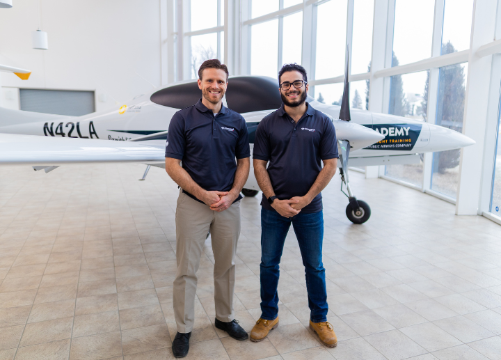 two men standing in front of an airplane.