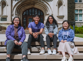 four students sitting on the steps outside UC on campus.