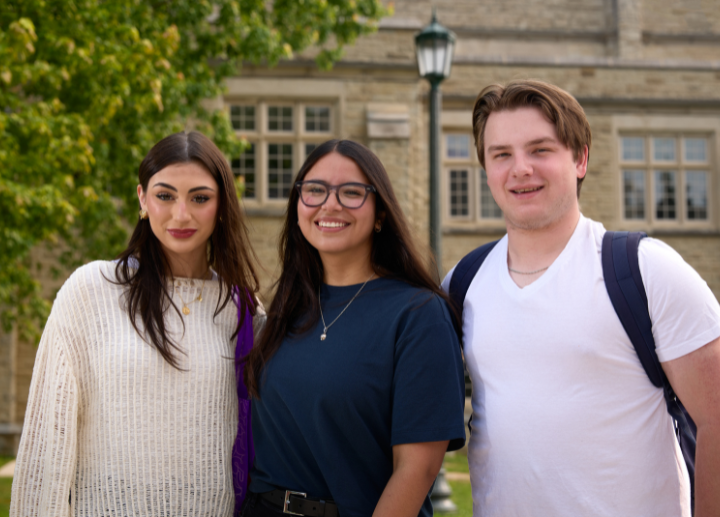 three student posing for a photo, smiling.