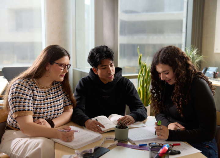 three students studying at a table.