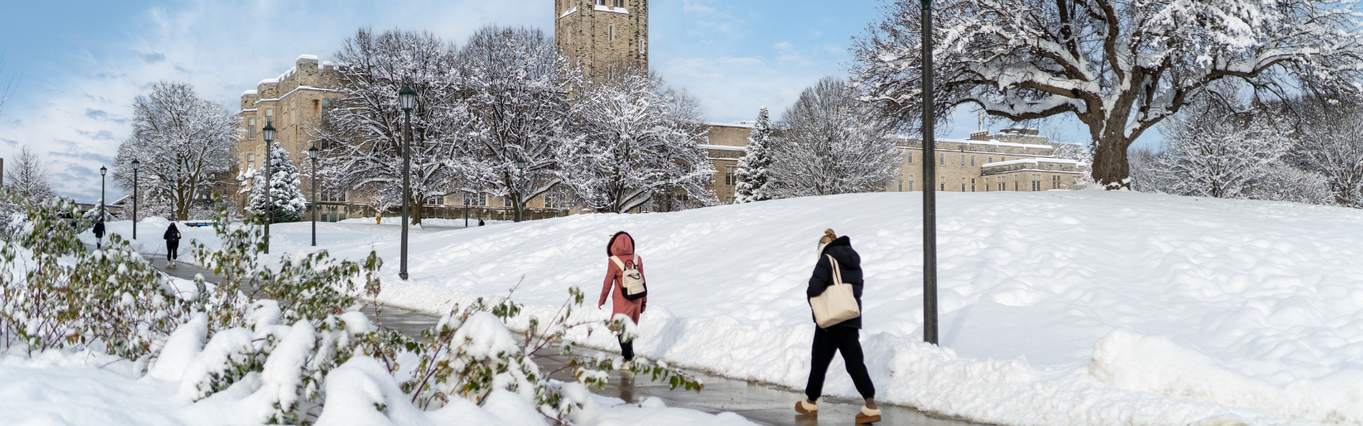 Two students walking outside UC during a snowy day.